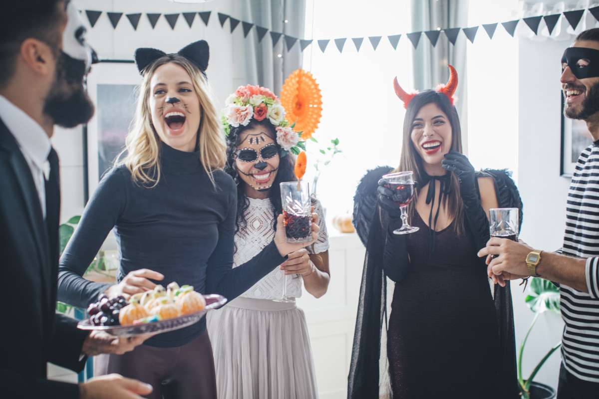 Hommes et femmes déguisées en train de rire lors d'une fête d'halloween en entreprise