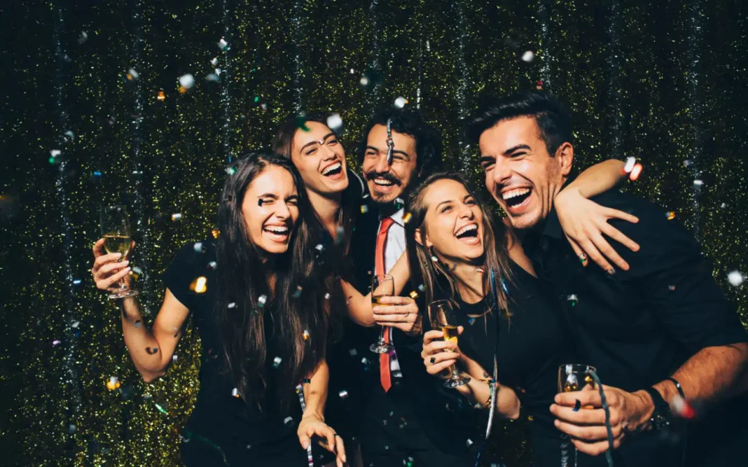 Des collègues souriants célébrant ensemble lors d'une fête de fin d'année en entreprise, entourés de confettis et d'une ambiance festive.